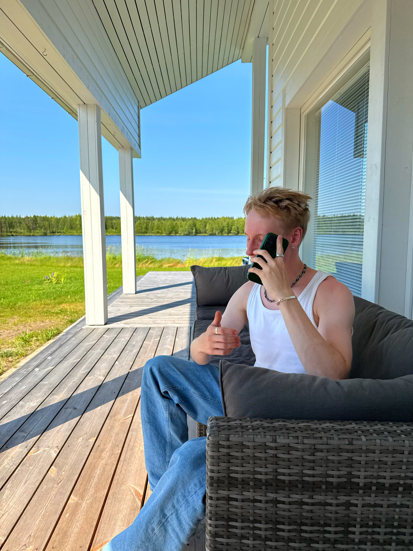 Jani puhelimessa mökin terassilla järven rannalla